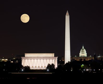 Full Harvest moon rising above the Lincoln Memorial with Washington Monument and Capitol building aligned