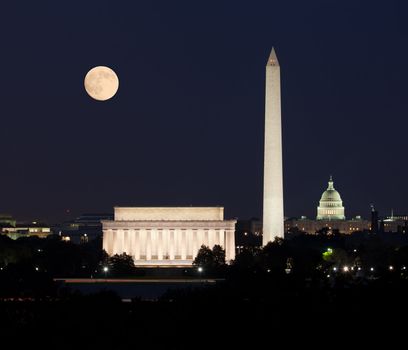 Full Harvest moon rising above the Lincoln Memorial with Washington Monument and Capitol building aligned