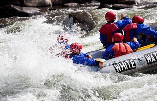 Group of adventurers in an inflatable dinghy in the white water of a fast moving river