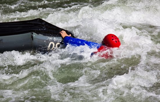 Canoeing in white water in rapids on river with the canoeist falling out of his boat