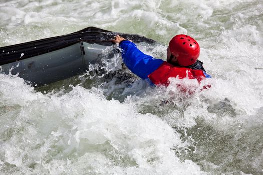 Canoeing in white water in rapids on river with the canoeist falling out of his boat