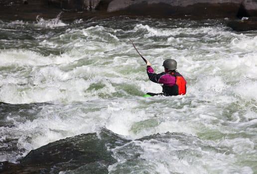 Canoeing in white water in rapids on river with the kayak starting to sink in the waves