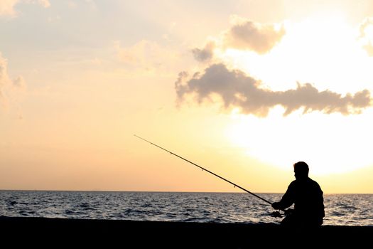 a man fishing at the sunset