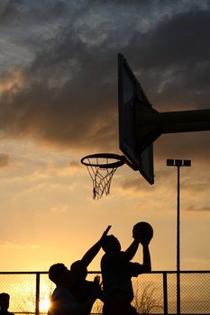 silhouettes of basketball players at the sunset