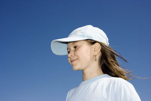 The smiling girl in a cap against a dark blue clear sky