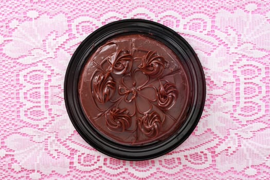 top view of a chocolate cake over a pink and white tablecloth