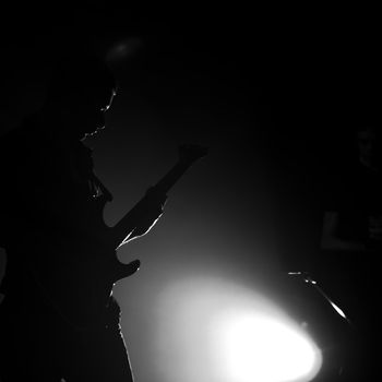 Black-and-white silhouette of the guitarist on a scene