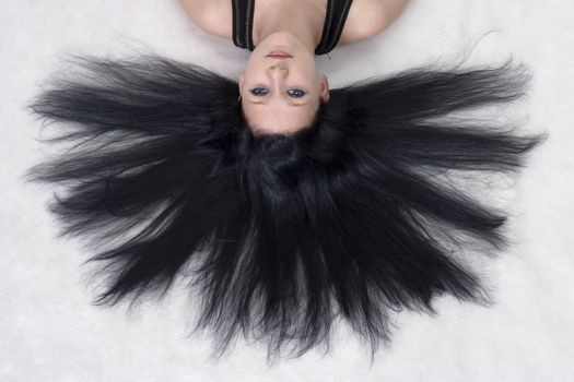 The girl with long black hair lying on a floor