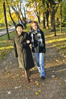 Teen granddaughter walking with grandmother in autumn park