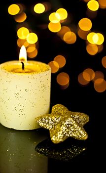 Candle with a star on a black background, back background Bokeh lights.
