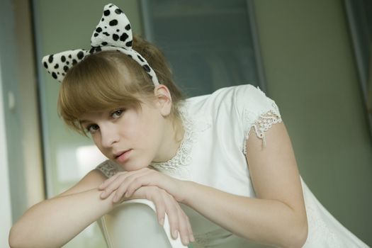 portrait of young cute thoughtful girl wearing white dress with dog`s ears
