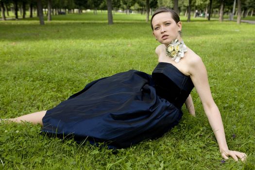 maid of honour with bouquet on neck sitting on grass