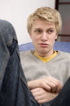closeup portrait of young blond sad crying man with blue eyes. Teen`s problem