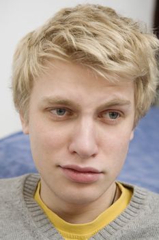 closeup portrait of young blond sad crying man with blue eyes. Teen`s problem