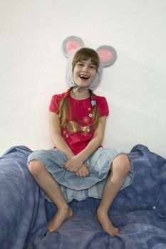 young cute laughing girl wearing mouses`s ears sitting on the sofa