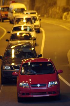 several cars in tunnel, first car red, jam