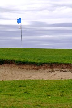 golf course; sand ditch, blue flag on post