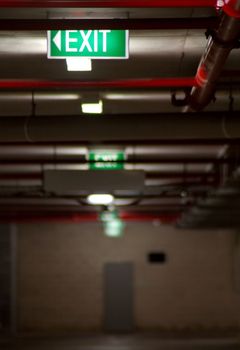 several exit signs in basement, distance blur, door