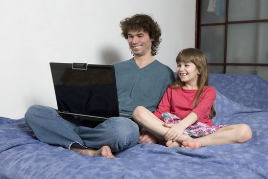 Father and daughter playing game sitting on the sofa using a laptop computer