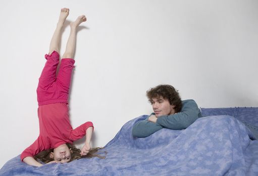 young smiling cute girl standing at head. Upside-down. Father watching it