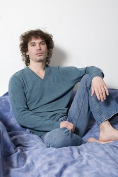 portrait middle-age serious curl man wearing blue pullover sitting on sofa. White background