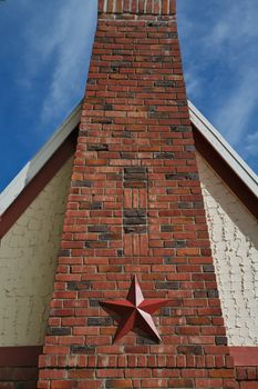Pyrimad like red brick home chimney with star decoration against a blue sky cloudscape