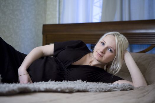 attractive pregnant blond  serious woman lying on bed