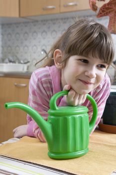 little cute girl seven years old with watering-can sitting on kitchen