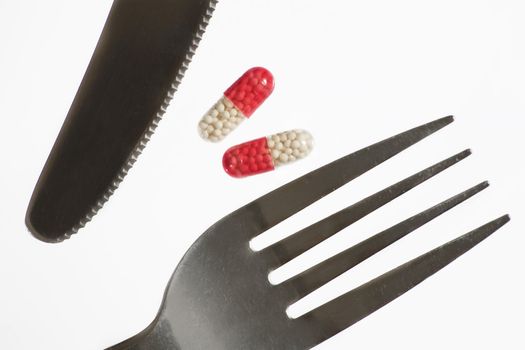 Dream about weight loss.  Fork, knife and pill. White background