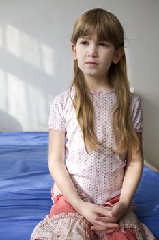 portrait young adorable cute serious girl sitting on bed
