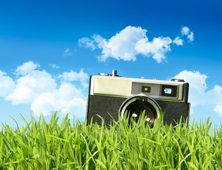 Vintage camera in tall grass against a blue sky