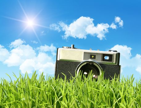 Vintage camera in tall grass against a blue sky