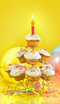 Lots of cupcakes on a muli-tiered stand against yellow background