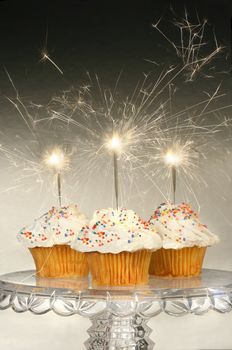 Cupcakes with sparklers on glass cake stand