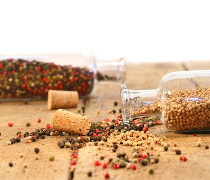 Peppercorns in glass bottles on rustic wood table