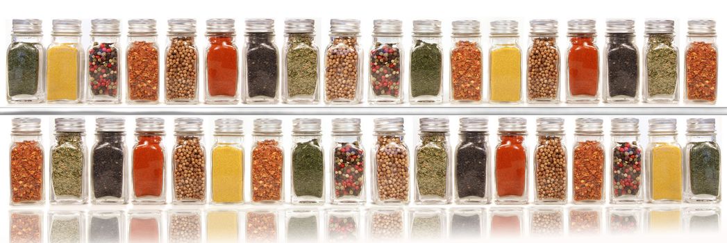 Assorted spices on two layer shelves against white background