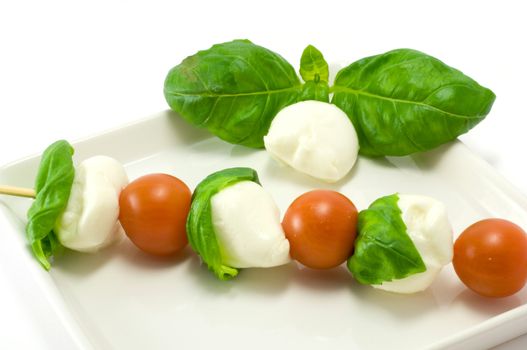 Caprese salad close-up with olive oil green basil and  pepper 