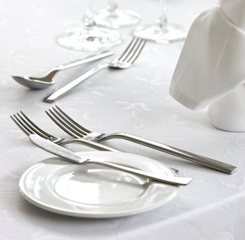 Knife, fork, spoon, plate and napkin on a table