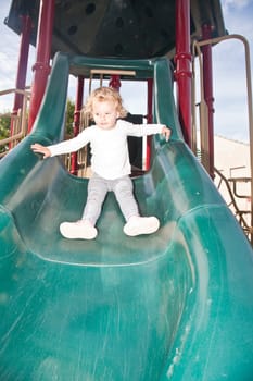 Cute little European toddler girl having fun at the playground in the park.