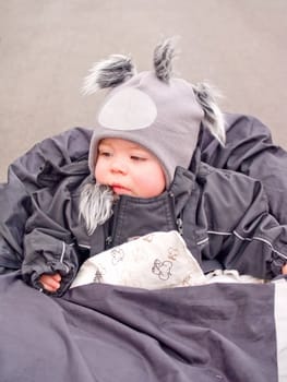 Cute Baby boy looking thoughtful sitting in pram outside