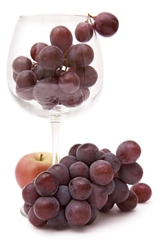 Grapes in a wine glass and an apple