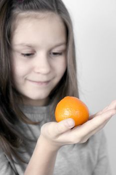 The girl holds a tangerine on a palm