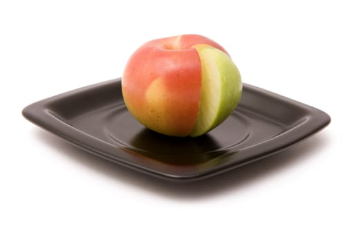 Apple and its segment on a black plate on a white background