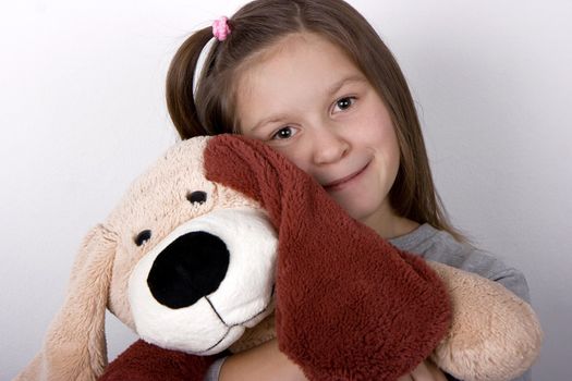 The happy girl embraces a toy dog