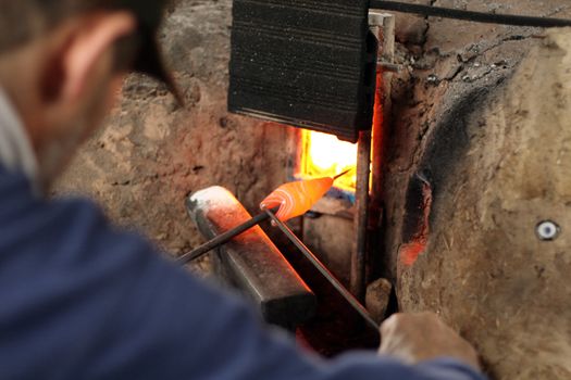 a man shaping a glass bead like a fish