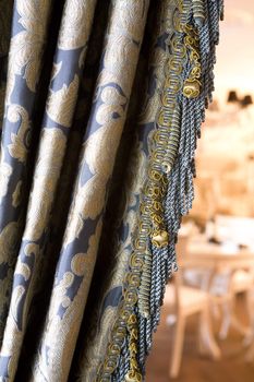 Luxurious curtain from woollen cloth with tassel. Blue and gold