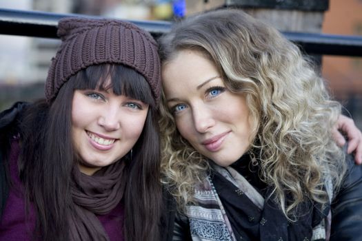 portrait of attractive embracing girls sitting on the bridge. London, UK