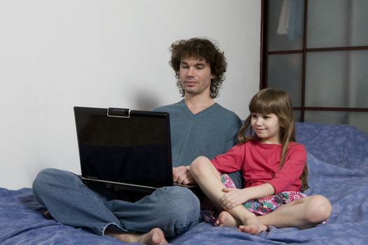 Father and daughter playing game sitting on the sofa using a laptop computer