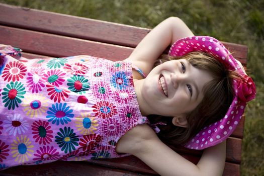 Little cute smiling girl six years old in panama lying on bench. Summer time
