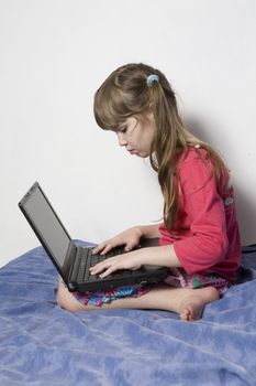Cute little girl seven years old playing with laptop
